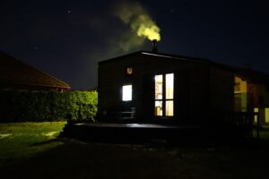 tiny house in dark with lights on and active chimney