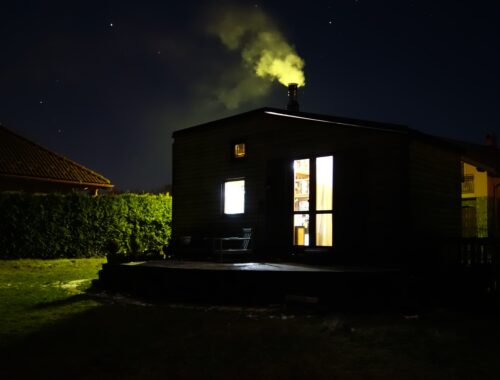 tiny house in dark with lights on and active chimney